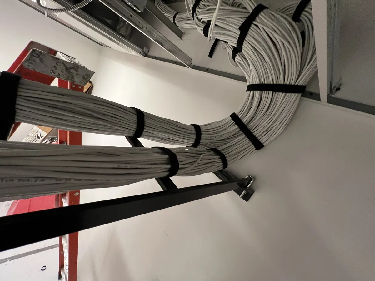 MDF room during commercial buildout — two-post rack, cable bundles routed through open ceiling