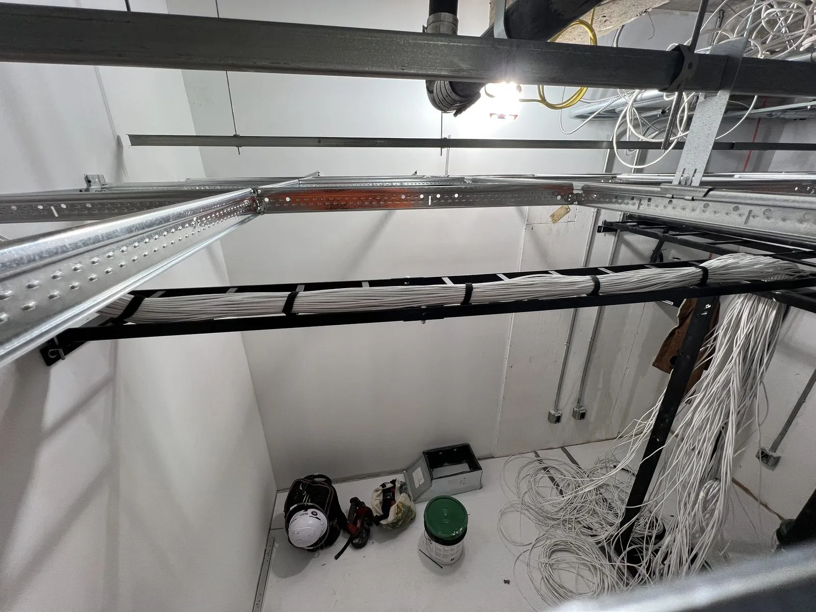 Overhead cable tray and category bundles run through an active NYC construction ceiling