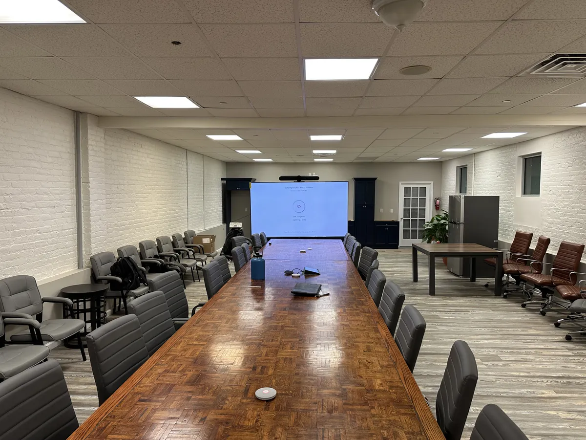 Large boardroom with long conference table and ceiling-mounted projection screen
