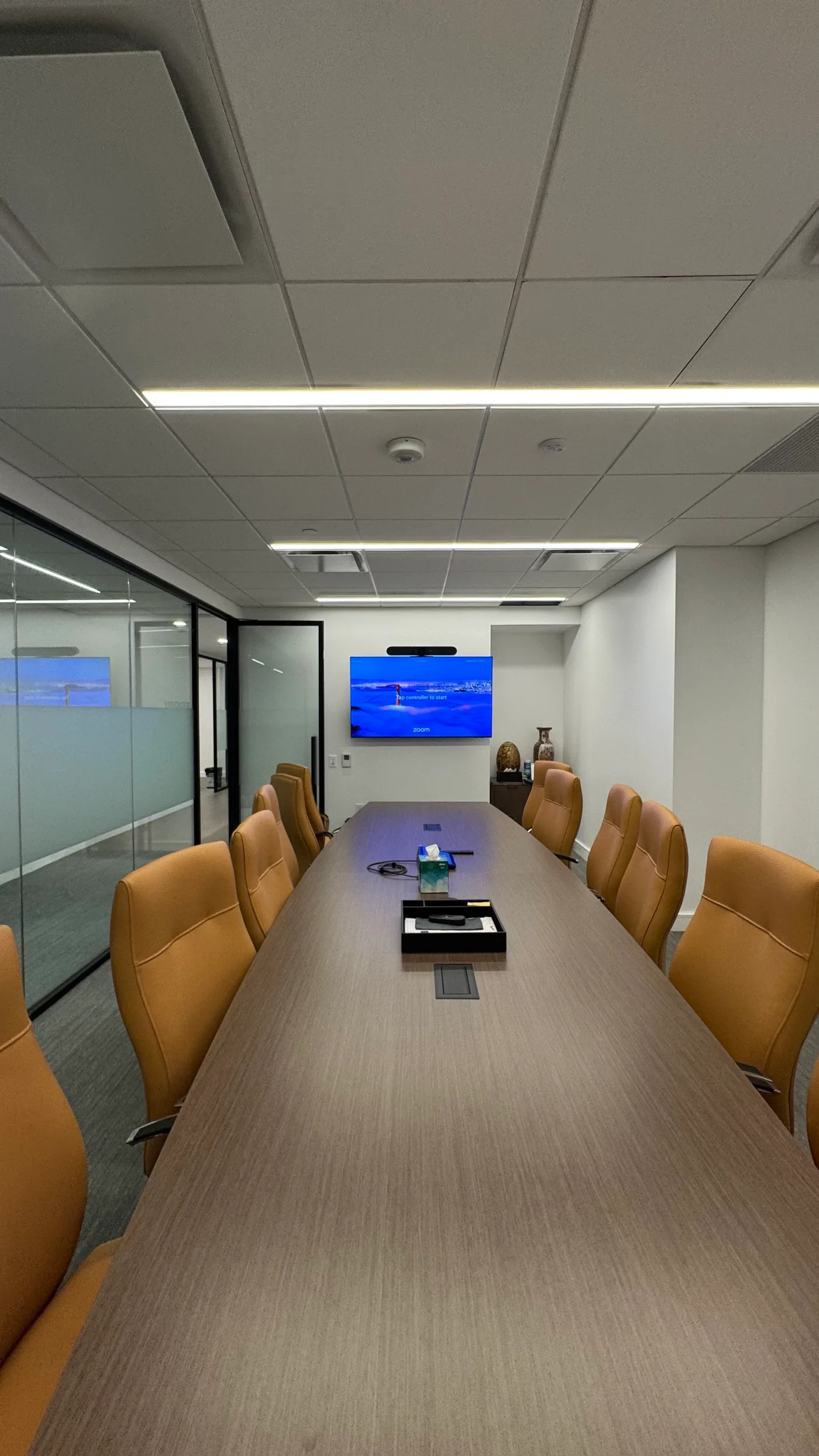 Executive boardroom with a Zoom Room video bar, wall-mounted display and leather seating