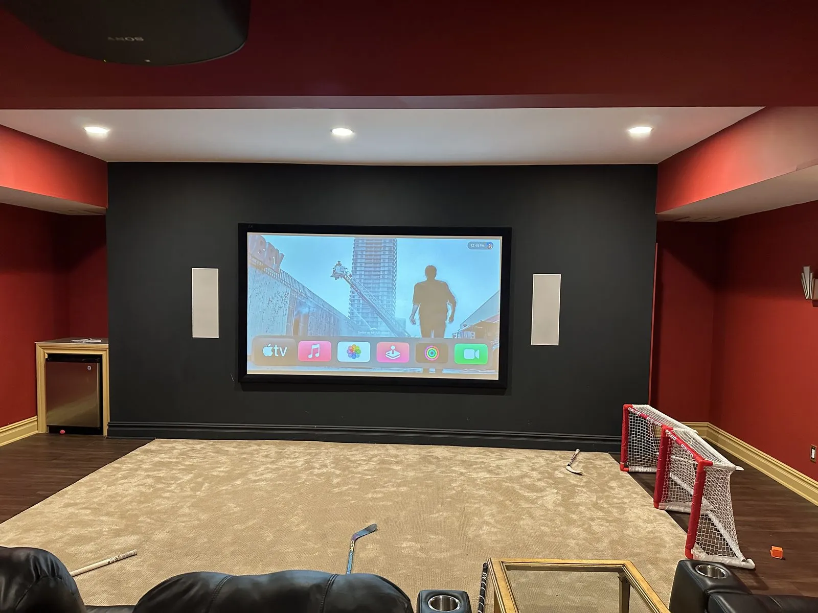 Home theater with ceiling-mounted projector, in-wall surround speakers, and Apple TV integration