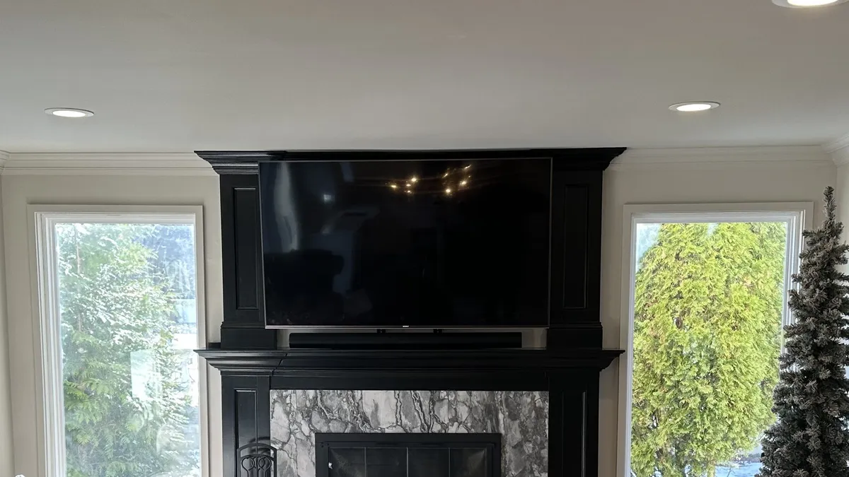 Living room TV integrated into black millwork above a marble fireplace with a soundbar