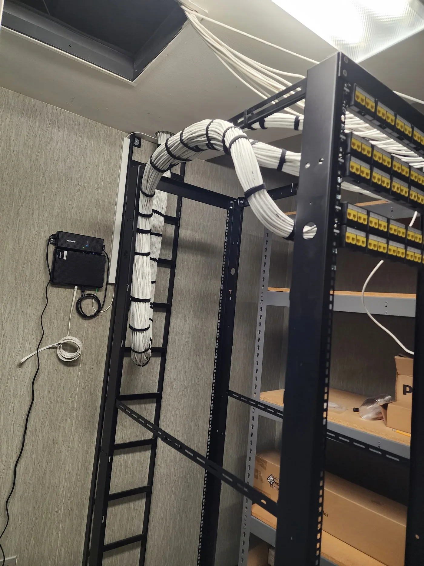 NYC server closet rough-in with wall-mounted patch panels, an ISP gateway and a spiral-wrapped cable riser into the rack